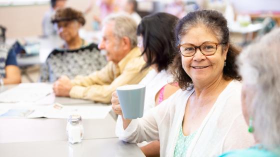 Woman with friends talking and having coffee in a senior center