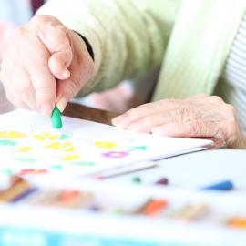 Crop senior patient drawing with crayon