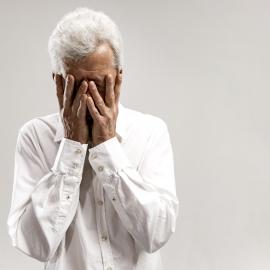 Portrait of upset old man covering face while crying. isolated on grey wall
