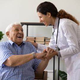 Positive young female nurse have fun laugh and joke with happy elderly male patient at consultation in hospital. Caring woman doctor support cheer and comfort mature man. Good medicine concept.